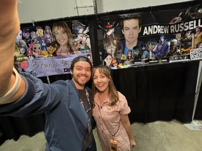 Andrew Russell taking a photo with a fan at his convention table
