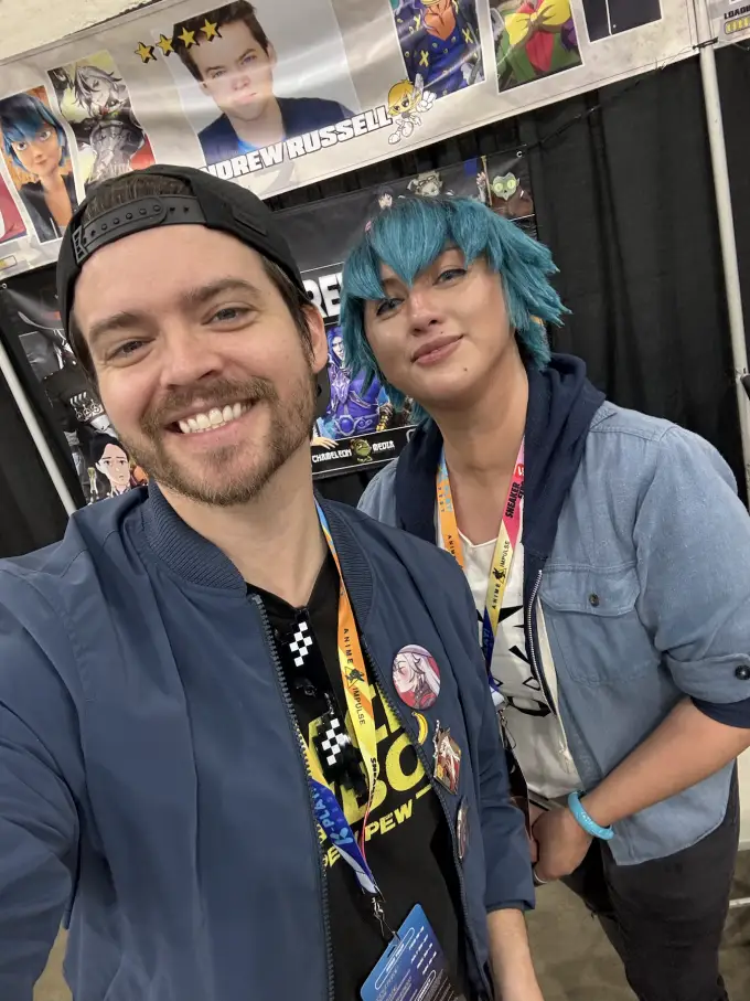 Andrew Russell smiling with a fan on the convention floor